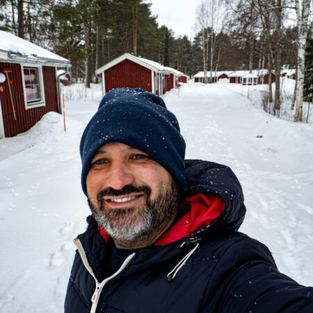 Pov of a man in winter clothes taking a smiling selfie in a snowy landscape in Sweden.
